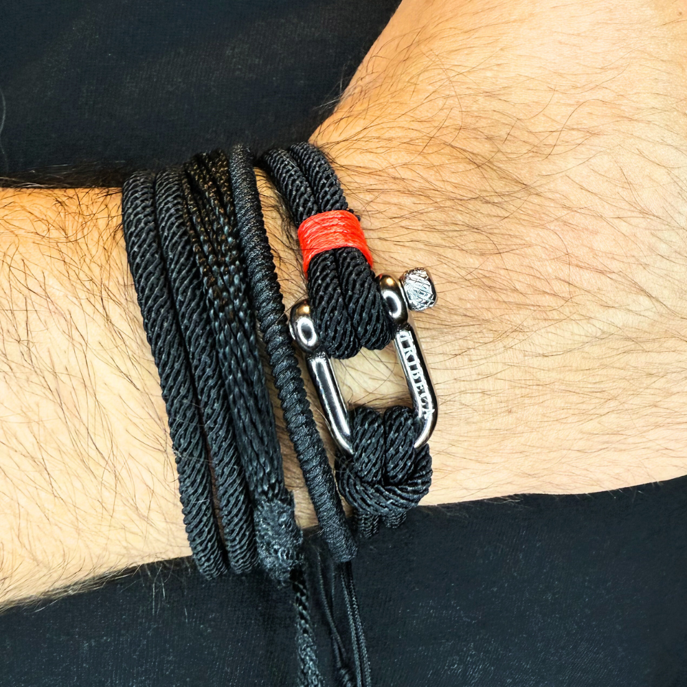 Black braided bracelet with a carabiner on a wrist against a black background