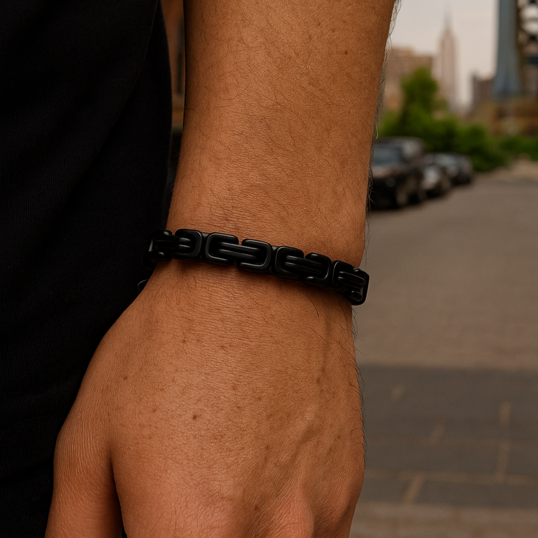 Close-up of a person's wrist wearing a black bracelet with a blurred background