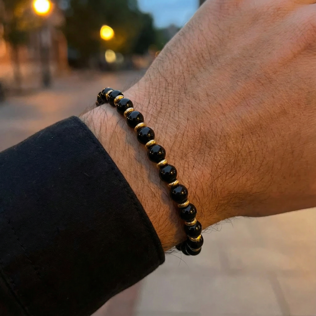 Black and gold beaded bracelet on a wrist with a blurred background