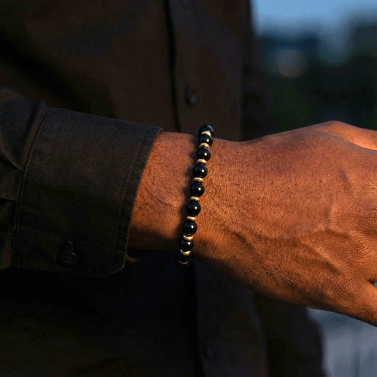 Close-up of a wrist wearing a black beaded bracelet with a blurred background