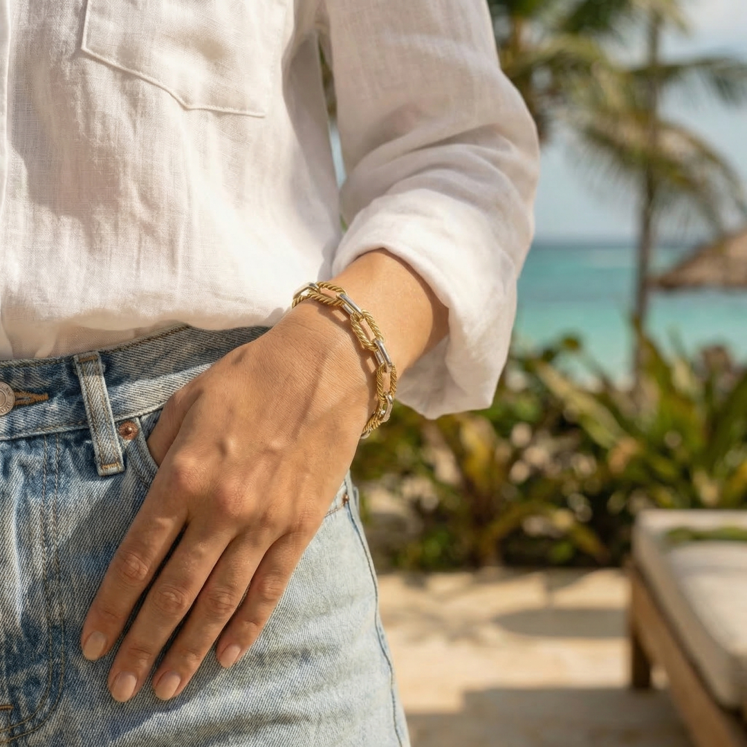 Woman wearing a gold bracelet with a beach and palm trees in the background
