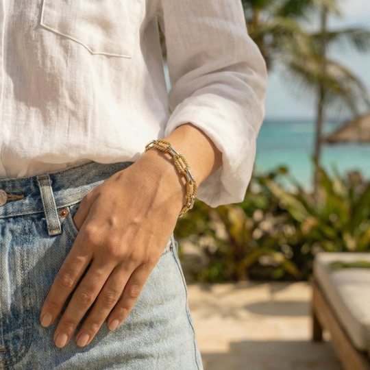 Woman wearing a gold bracelet with a beach and palm trees in the background
