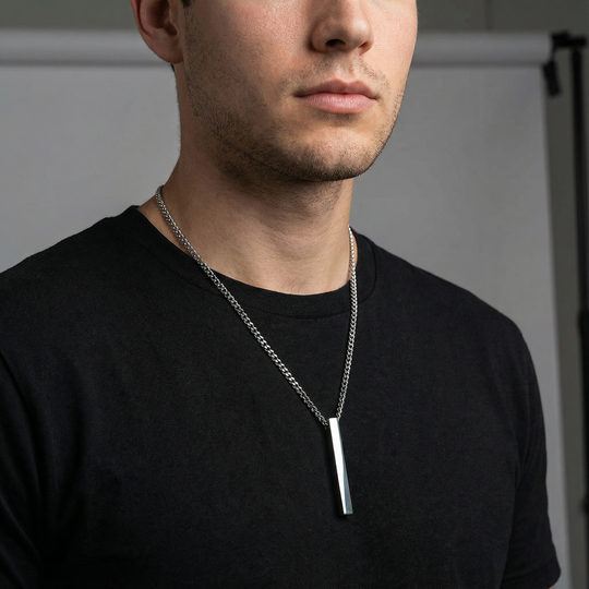 Man wearing a black shirt with a stainless steel necklace featuring a rectangular pendant.