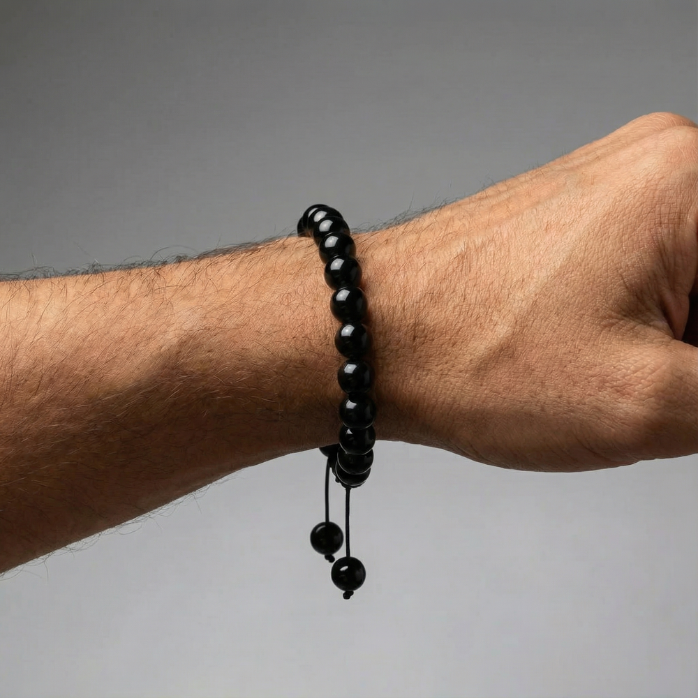 Black beaded bracelet on a wrist against a gray background