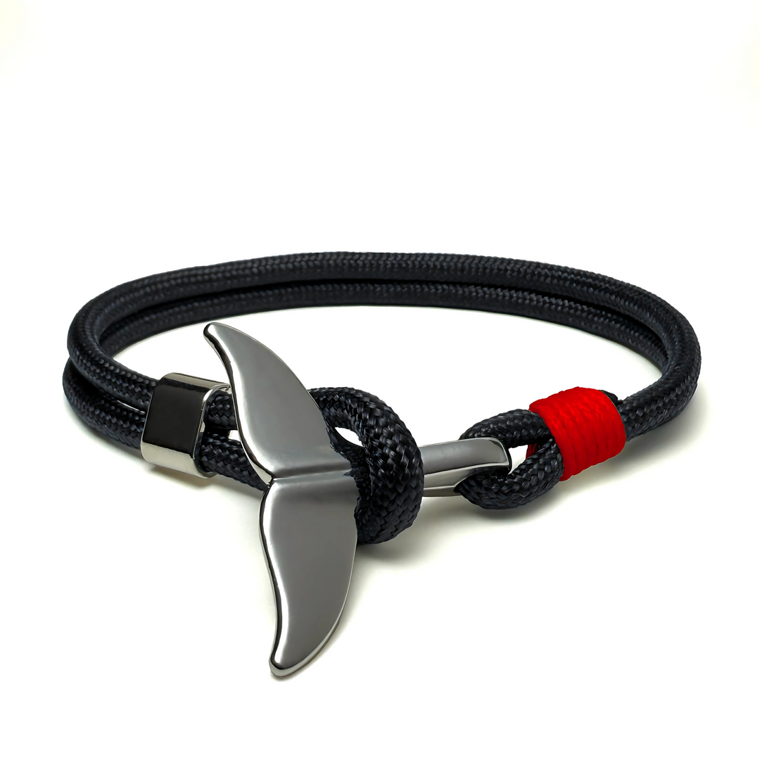 A black and red bracelet with a metallic whale tail charm.