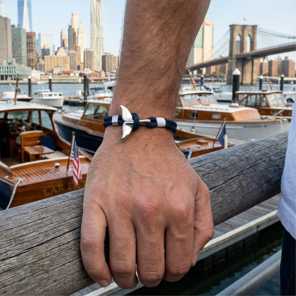 Hand wearing a bracelet with a city skyline and boats in the background