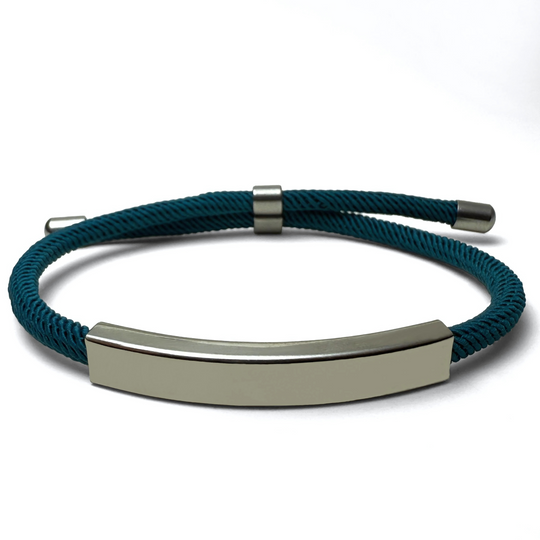 A teal-colored bracelet with a metallic bar centerpiece, displayed against a white background