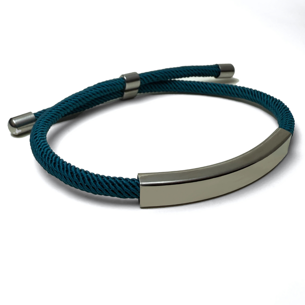 An angle shot of a teal-colored bracelet with a metallic bar centerpiece, displayed against a white background
