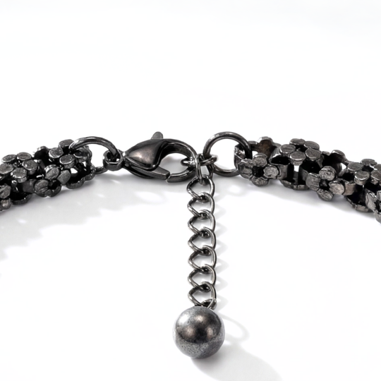 Close-up of a black chain bracelet with a lobster clasp and spherical charm on a white background