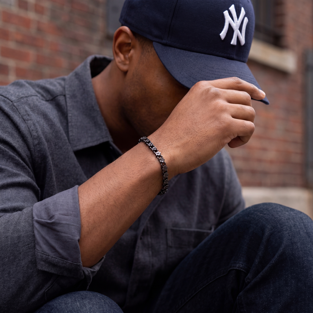 Man wearing a navy blue cap with a logo, sitting against a brick wall.