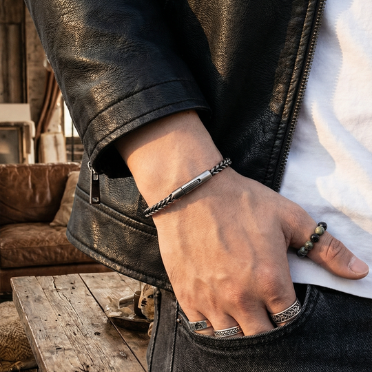 Person wearing a leather jacket with a bracelet on his wrist and rings on multiple fingers
