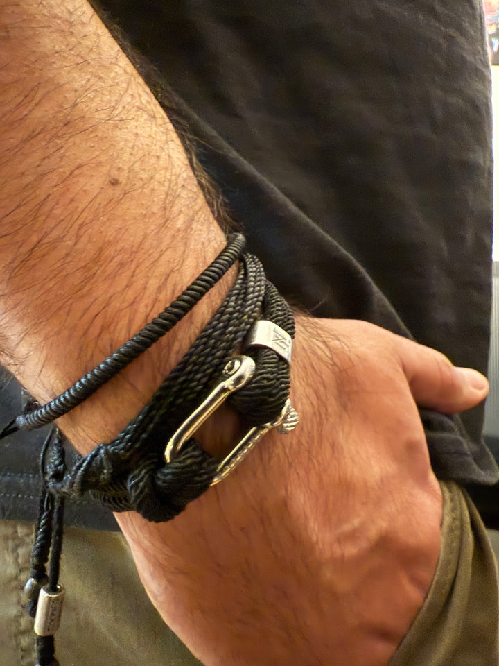 A man's wrist with a group of black rope bracelets