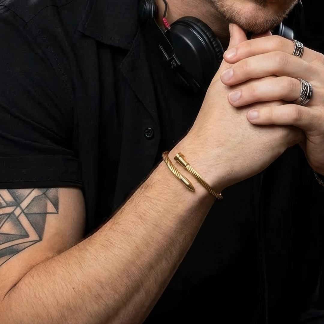 Person wearing a gold bracelet with a black shirt and tattoo on arm