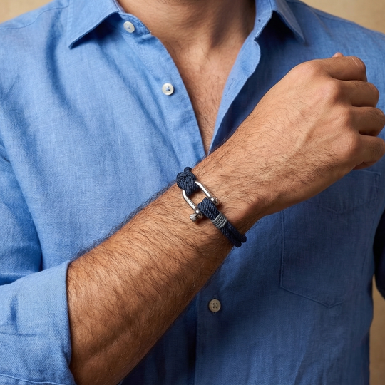 A man wearing a navy blue rope bracelet with a metal clasp 