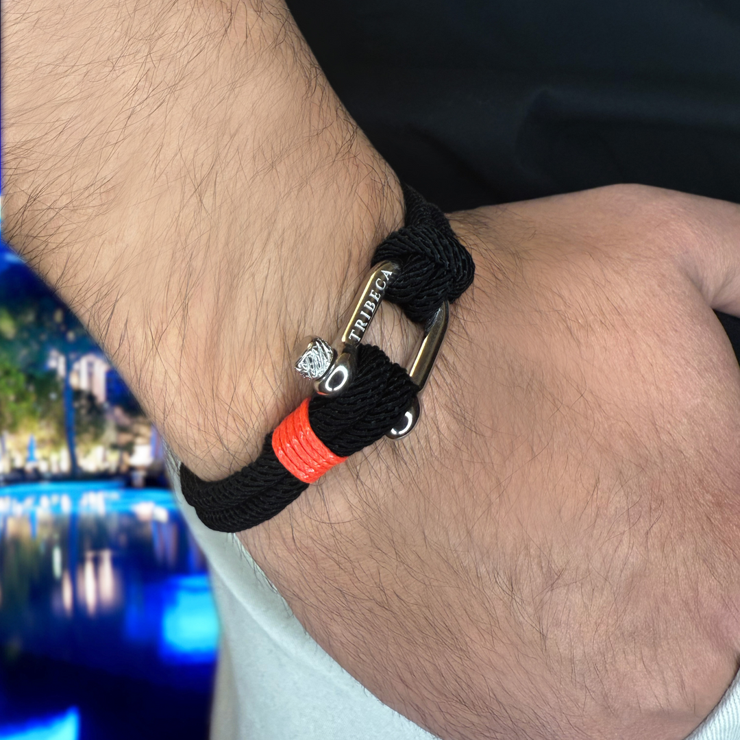 A black and red rope bracelet with a metal clasp on a man's wrist