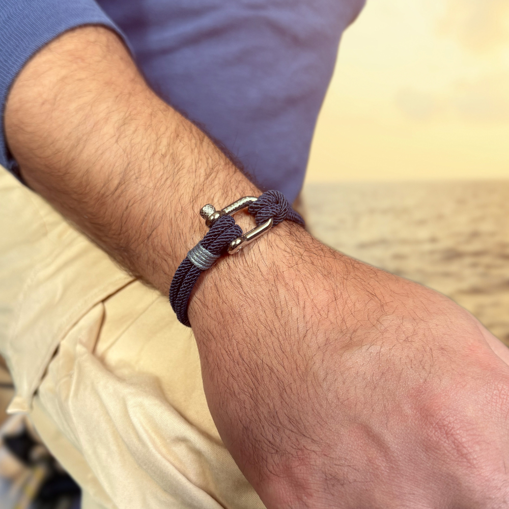 Close-up of a wrist wearing a blue bracelet with a metal clasp with a blurred background