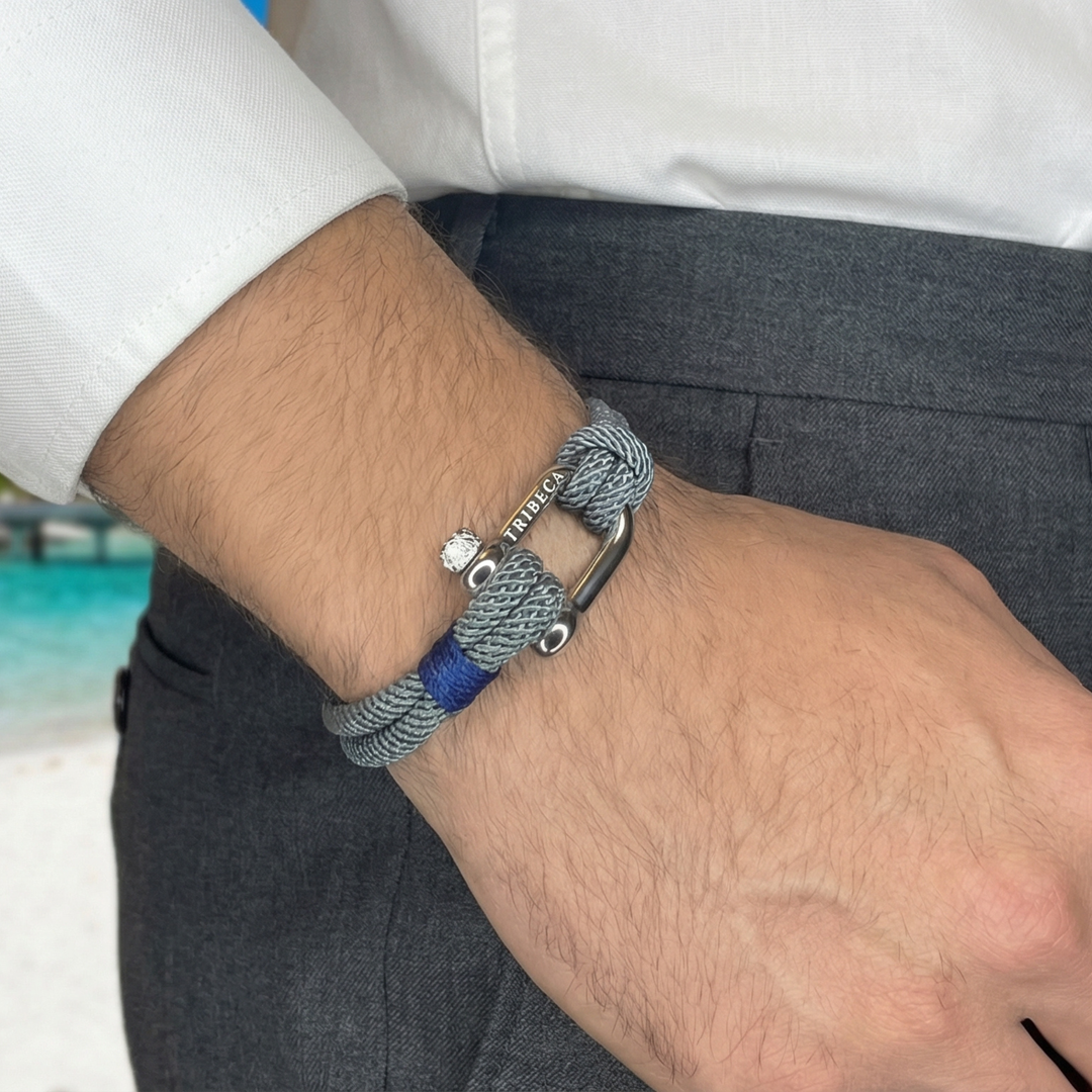 Close-up of a wrist wearing a bracelet with a beach in the background