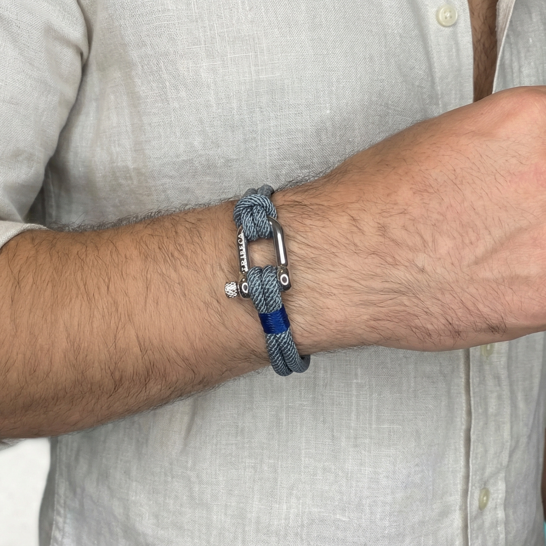 Close-up of a wrist wearing a blue braided bracelet with a metal clasp.