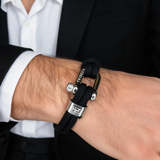 Black braided bracelet with silver clasp on a wrist, wearing a suit.