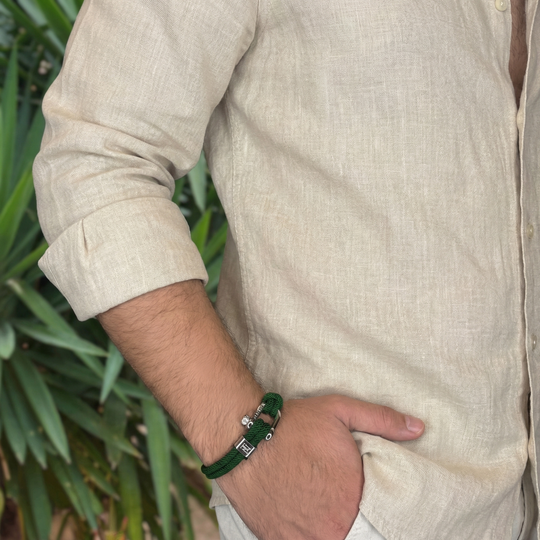 A man wearing a linen shirt with a green rope bracelet with metal clasps 