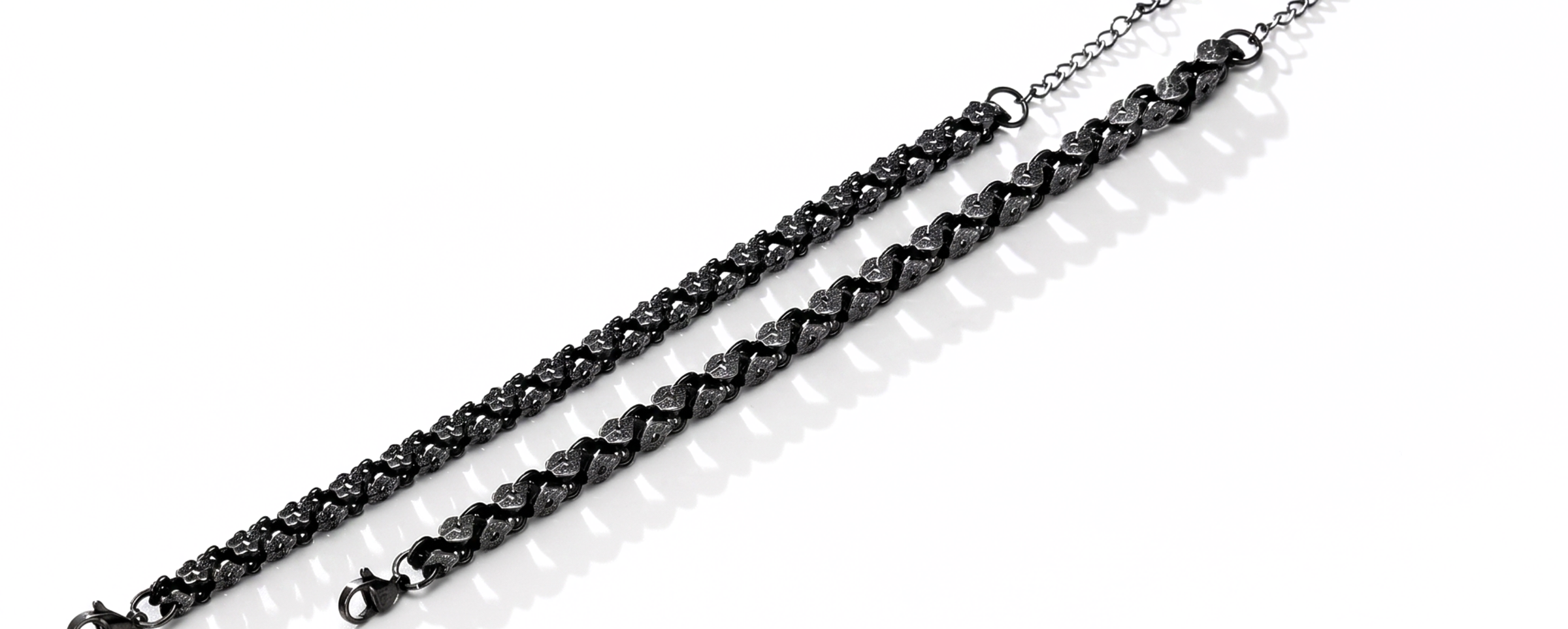 Two metallic chains with a floral and circular pattern on a white on a white background