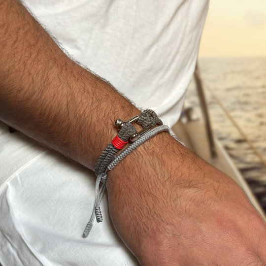 Close-up of a wrist wearing a gray bracelet with red accents, blurred background